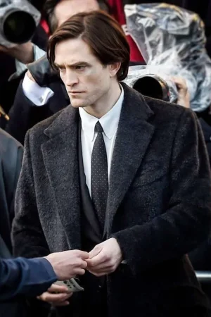Close-up of the lapel collar and full-length sleeves of Robert Pattinson’s black wool coat, showing detailed craftsmanship.