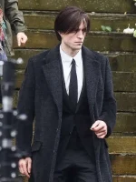 Robert Pattinson in a front-facing shot, wearing The Batman black wool coat, emphasizing the coat's lapel collar and sleek design.